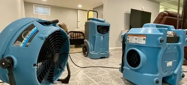 Air movers and a dehumidifier running in a room during a water damage dry-out