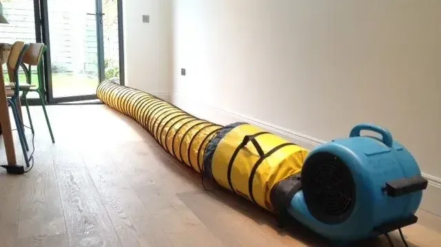 Air mover and duct blowing across a room with hardwood floors
