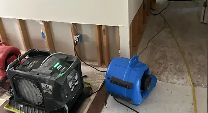 Air mover and dehumidifier drying drywall that was cut above the floor