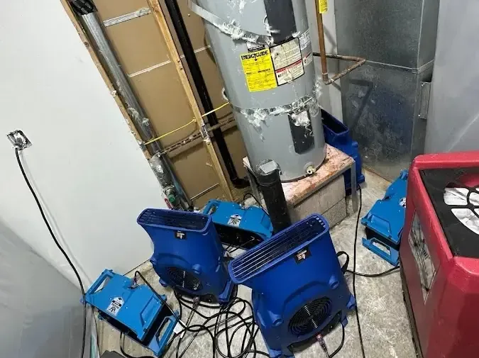 Air movers and a dehumidifier drying a water heater closet