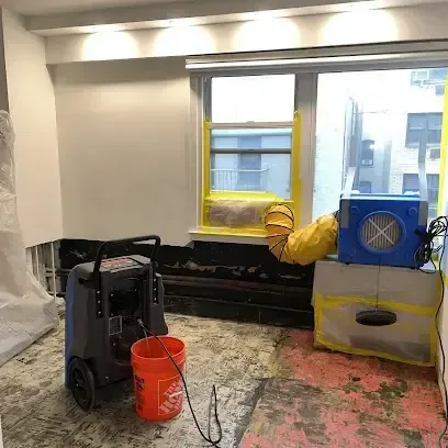 Dehumidifier and air mover drying a room where the flooring has been removed