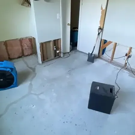 Air movers and a dehumidifier drying a room after the lower drywall was removed