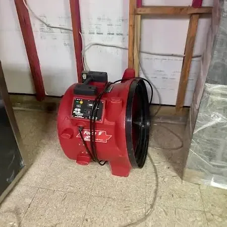 Pump hose and drying fans set up in a basement after outside water came in