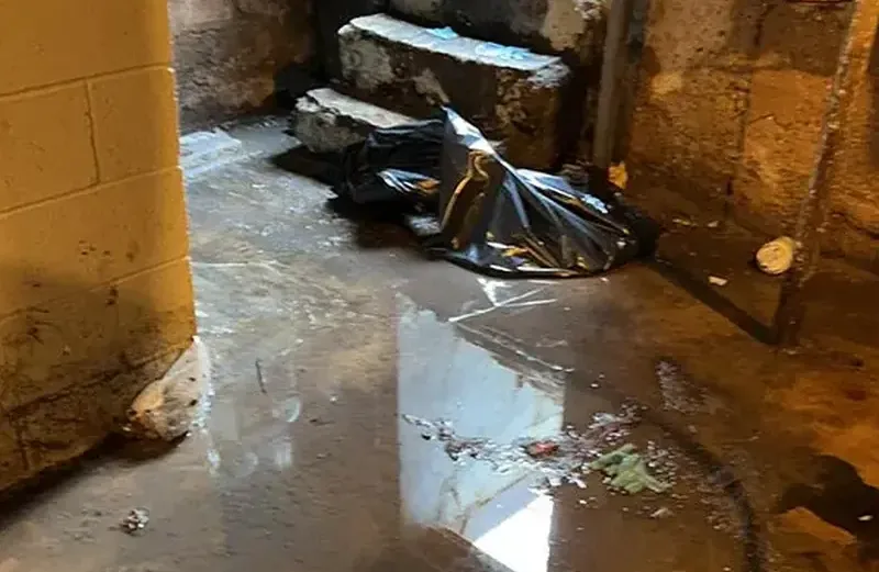 Workers in protective suits and respirators cleaning up after a sewage backup