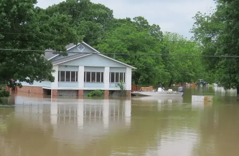 A house surrounded by brown floodwater after heavy rain